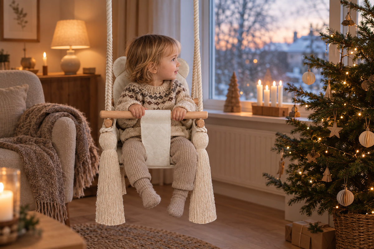 Barn i en babygynge i natur fløjl i en hyggelig stue med juletræ og levende lys i decemberlys